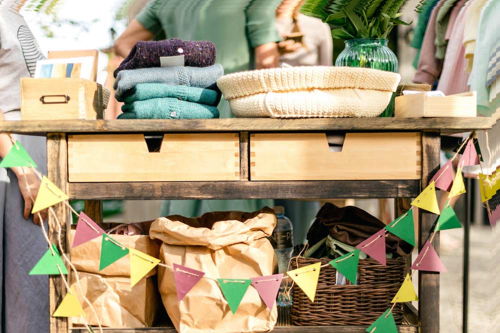 Färgglada flaggor, hantverkspåsar och varor för garageförsäljning på sommarens vintagefestival marknad