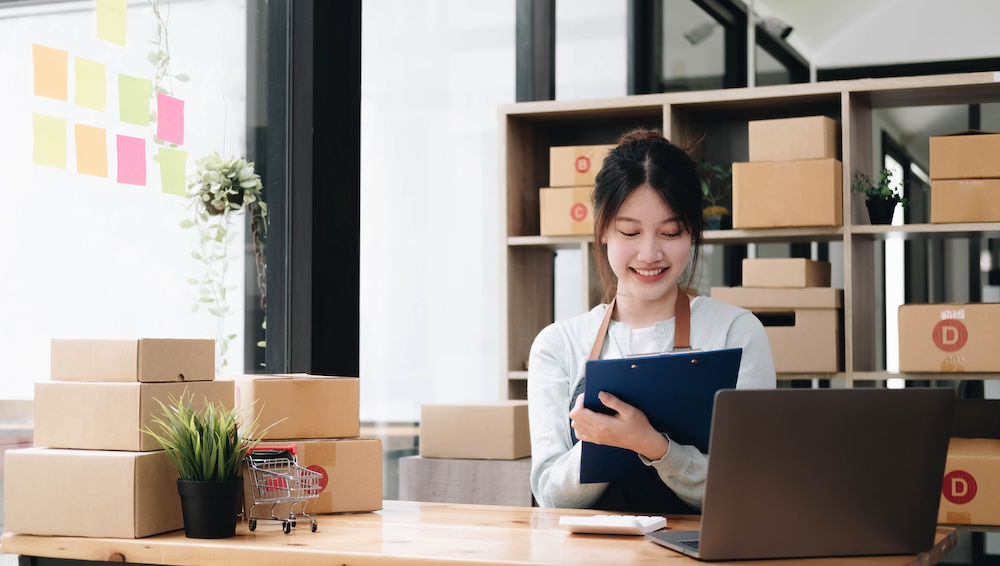 Ung asiatisk kvinna som jobbar med en e-handel på ett kontor